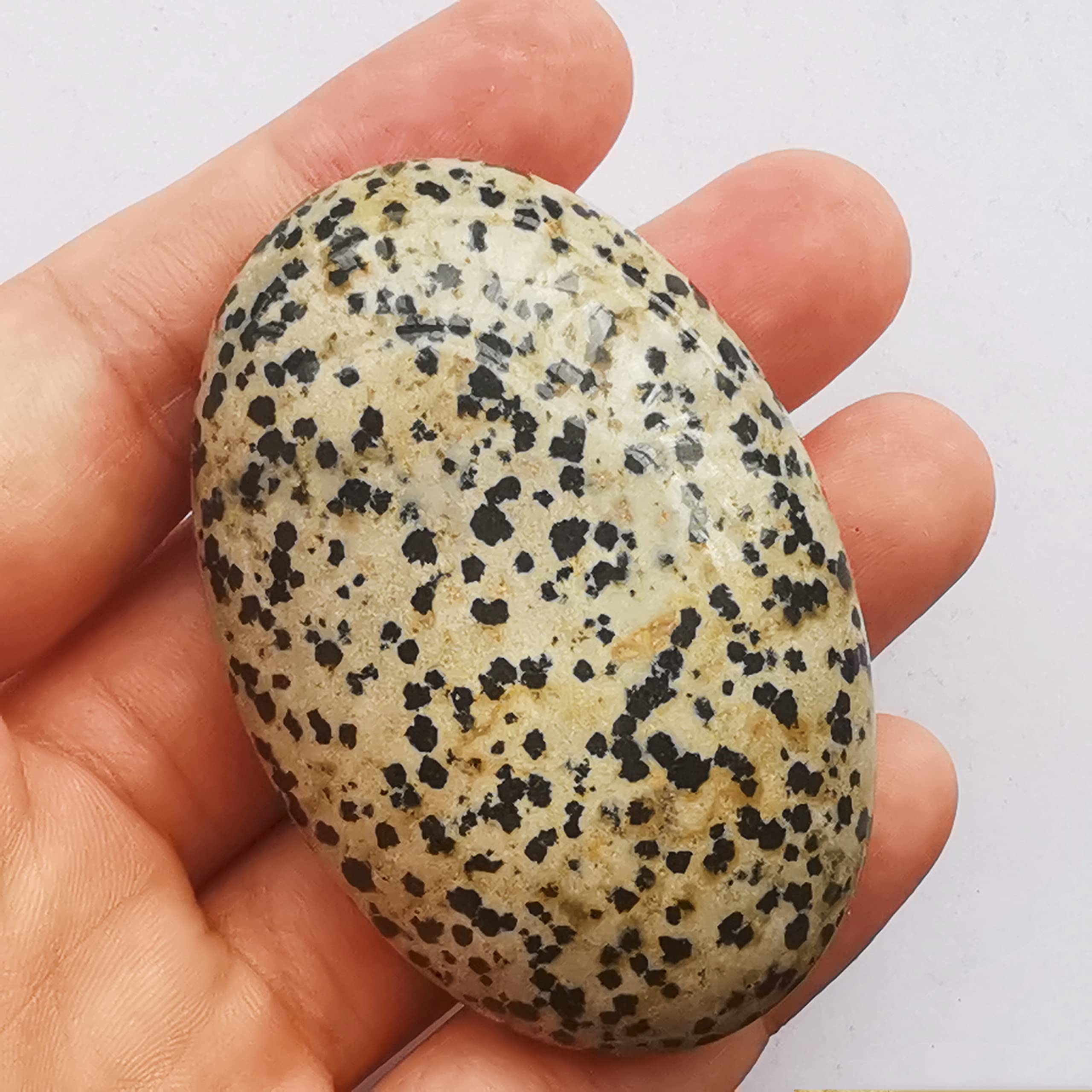 Piedra ovalada de Bacatgem en palma, tacto suave para masaje relajante.