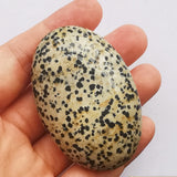 Piedra ovalada de Bacatgem en palma, tacto suave para masaje relajante.