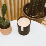 Tarro negro mate de Calyan Musk & Teakwood sobre mesa de madera