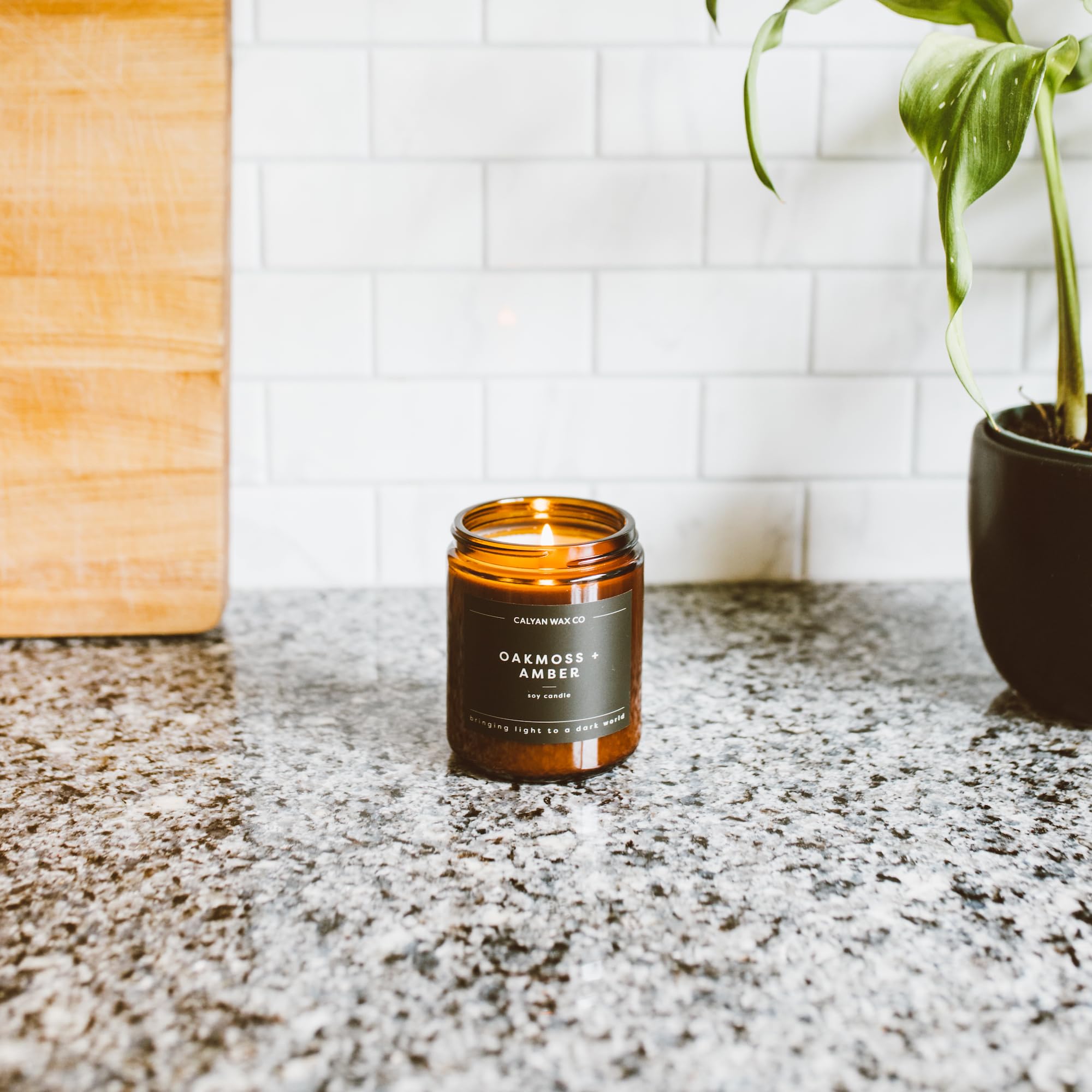 Vela encendida Calyan Wax Co. en salón, crea iluminación cálida y acogedora.
