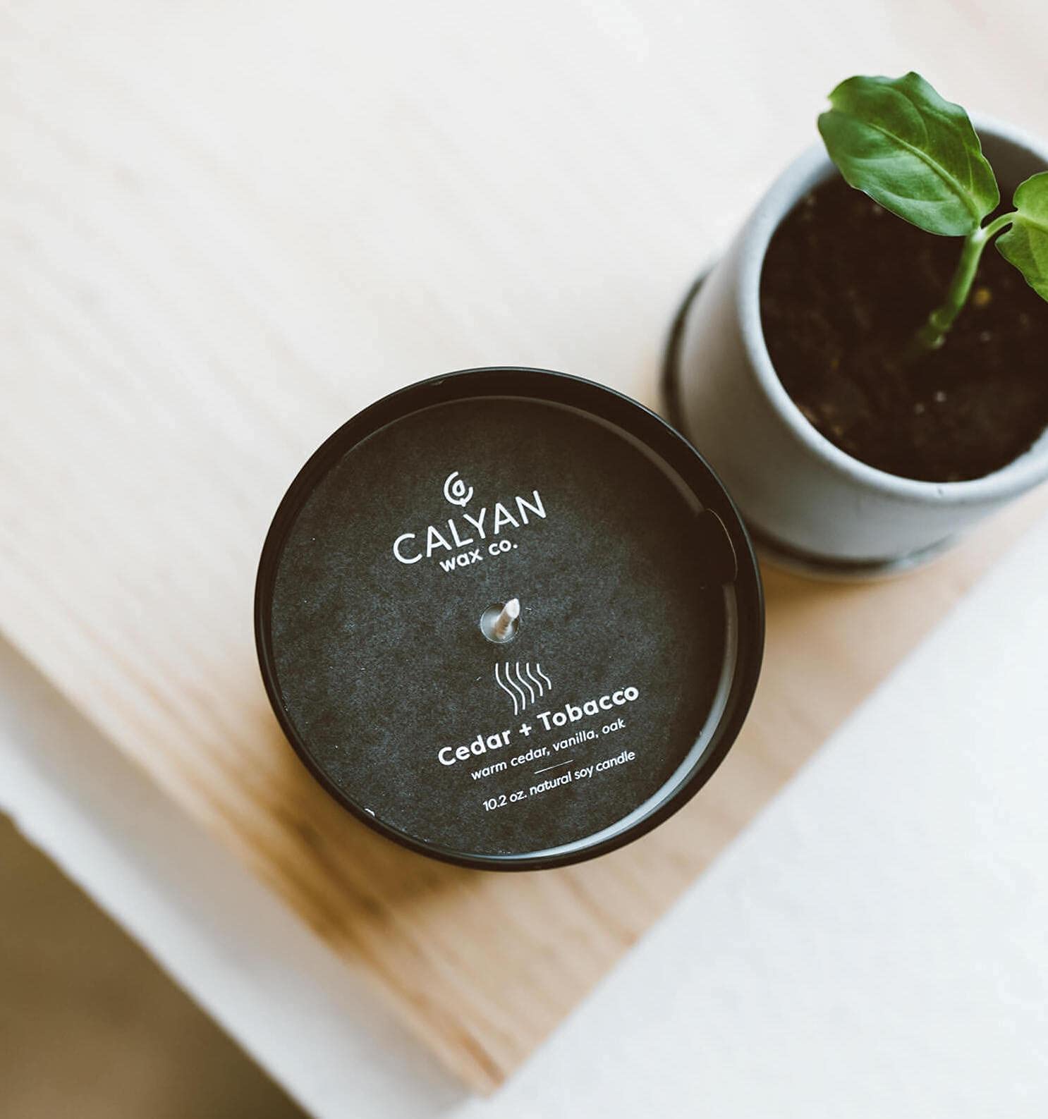 Calyan Wax Co. vela Cedar & Tobacco en dormitorio amplio, creando ambiente relajante.