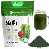Kate Naturals Super Greens polvo en vaso de agua para una bebida saludable.