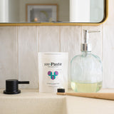 Envase con base plana de Unpaste para un soporte estable en el baño.